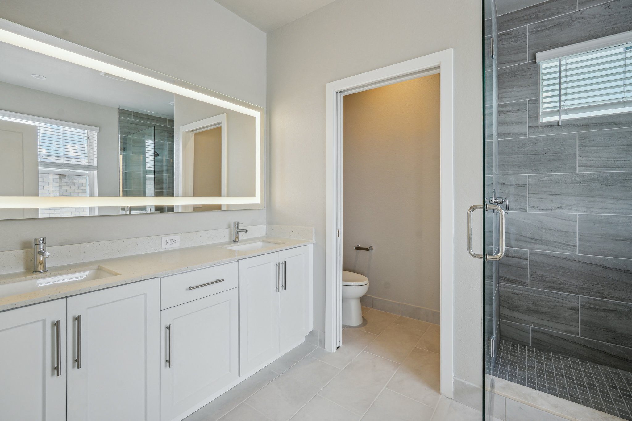 a bathroom with white cabinets and a shower and a sink